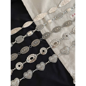 Ceintures chaîne en métal argenté avec motifs de feuilles et ovales sur tissu noir
