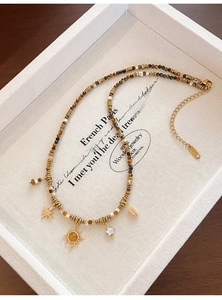 Detail of beaded necklace featuring sun and star pendants with tiger eye stones