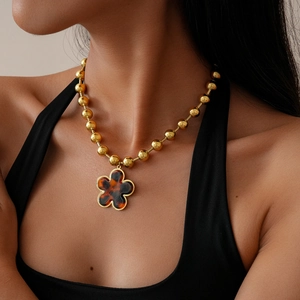 Detail of vintage gold beaded necklace with a tortoiseshell flower pendant on a model