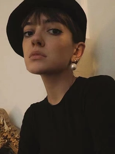 Close-up of 14K gold-plated round resin pearl hoop earrings on a female model with a black hat