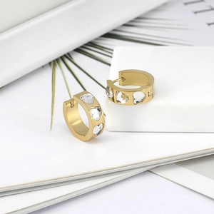 Détail de boucles d'oreilles créoles dorées 18k avec trois zircons brillants en cœur