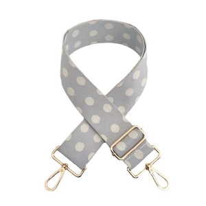 Close-up of adjustable gray shoulder strap with white polka dots and gold swivel hooks