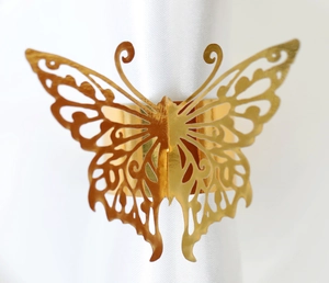 Close-up of golden laser-cut butterfly napkin ring on white silk fabric background