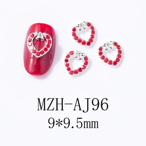 Macro detail of red heart-shaped nail charm with silver base on red manicure surface