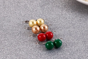 Détail de boucles d'oreilles perles en quatre couleurs sur fond gris scintillant