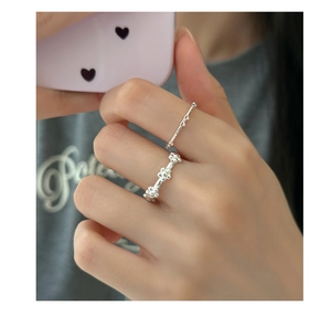 Close-up of a silver bow and floral sterling silver ring set on a hand model
