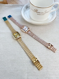 Close-up of gold and rose gold square watches on elegant textured cloth with china