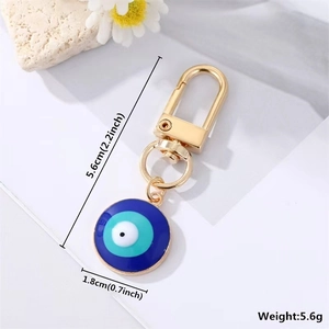 Detail view of evil eye keychain with gold finish and blue enamel showing dimensions