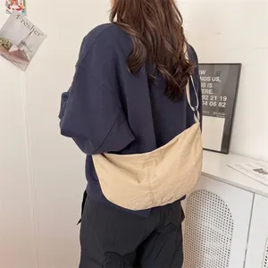 Detail view of khaki crescent canvas crossbody bag worn by a model in casual home setting