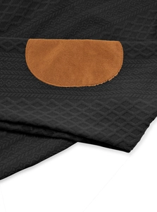Detail shot of black knitted fabric with a brown suede elbow patch and diamond texture