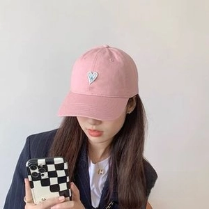 Close-up of pink cotton sun hat with heart patch on female model for beach and cycling