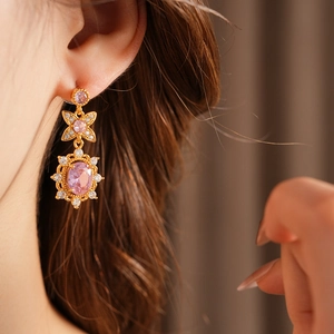 Close-up of vintage gold earrings featuring large pink gemstones and white zircons