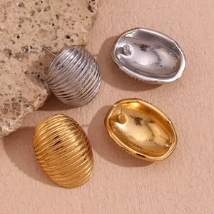 Detail showing gold and silver oval earrings with textured striped ripple patterns