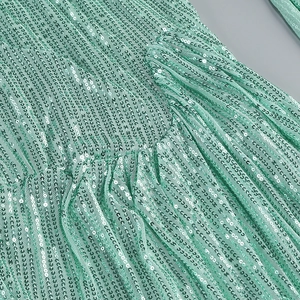 Detailed close-up of mint green sequin fabric with pleated texture and mesh layering