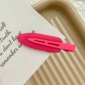 Detail of a matte rose pink seamless duckbill hair clip on a decorative paper card