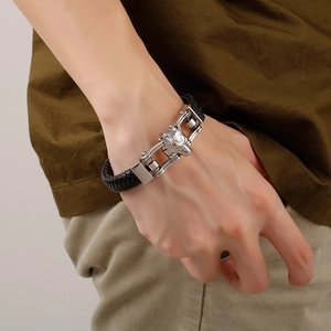 Men's braided leather bracelet featuring a silver wolf head clasp on a model's wrist
