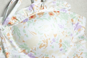 Detail of ruffled floral print fabric in purple and orange with delicate stitching