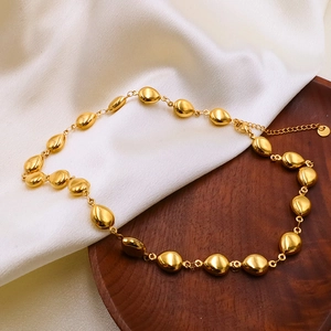 Detail of 18k gold plated stainless steel bead chain with lobster clasp on silk background