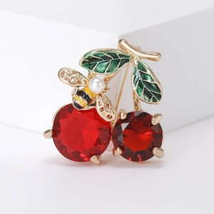 Detail of red crystal cherry brooch with green leaves and gold bee featuring a pearl