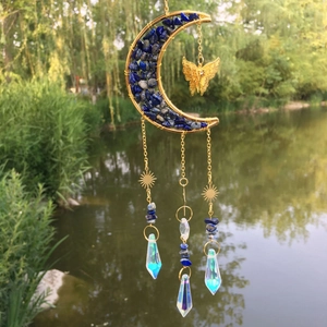 Detail of moon-shaped suncatcher with lapis lazuli stones and crystal prisms hanging outdoors