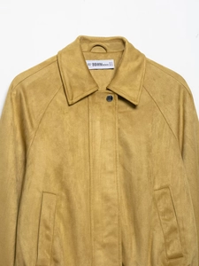 Detail of suede-effect bomber jacket showing mustard yellow collar and snap button closure