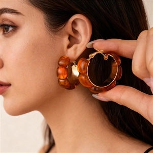 Maillard style amber resin hoop earrings with gold metal fasteners worn by a model