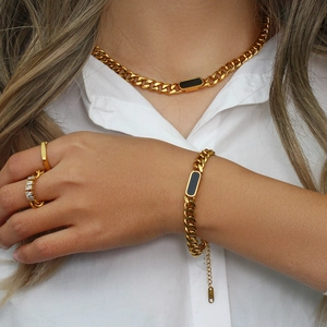 Close-up of 18K gold Cuban link chain set with black rectangle charms and rings