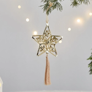 Golden hollow star Christmas tree ornament with pink tassel on festive pine branch