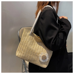Detail of straw woven tote bag with white daisy flower and rope handle strap