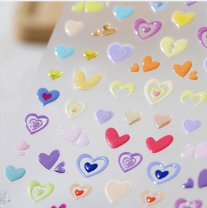 Detailed macro view of 3D embossed colorful heart nail art stickers with resin texture