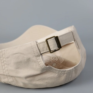 Detail van de verstelbare metalen gesp op de beige katoenen honkbalpet in vintage-stijl