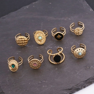 Top view of eight vintage gold open rings with colorful gemstones on a dark stone surface