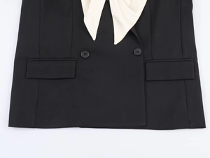 Detail of black double-breasted blazer with white contrast collar and woven fabric texture