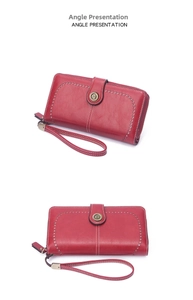 Red leather long wallet for women with vintage punch design, wrist strap and zipper closure.