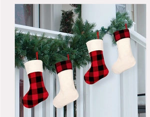 Close-up of four red and black buffalo plaid Christmas stockings hanging on a white railing