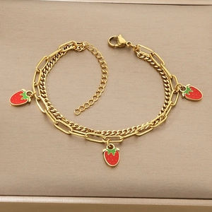 Close-up of dual-layer gold chain bracelet with three red enamel strawberry charms