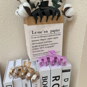 Gros plan sur des pinces à cheveux en acétate noires, violettes et ambre avec décor