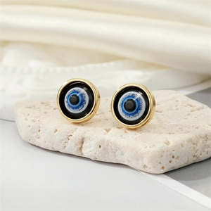 Macro shot of evil eye stud earring with gold rim on natural stone background
