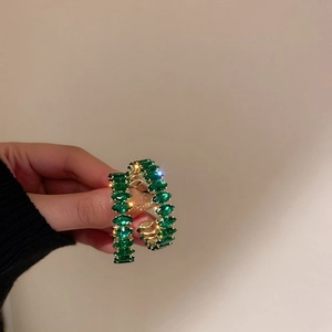 Pendientes vintage dorados con circonitas verde esmeralda marquesa sostenidos en la mano