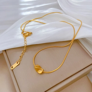 Detail of gold snake chain necklace with bean pendant and S.Steel hallmark on silk