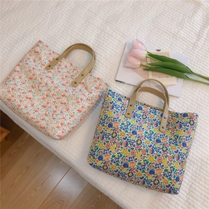 Close-up of floral canvas tote bags with leather handles and metallic rivets detail