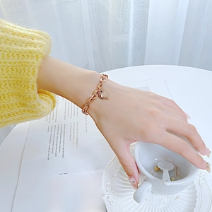 Close-up of gold heart pendant bracelet with rectangular links worn by a model