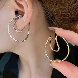 Close-up of polished irregular twisted metal ear cuffs in gold and silver finishes