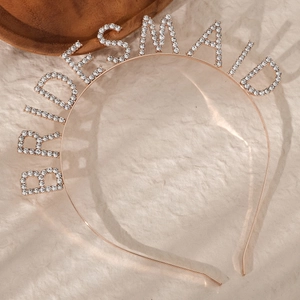 Close-up of golden bridesmaid headband featuring sparkling rhinestones on textured paper