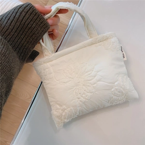 Dettaglio della borsa trapuntata bianca con ricamo floreale ed etichetta del marchio