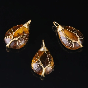 Three tiger eye tree of life teardrop pendants with gold wire wrapping on black background