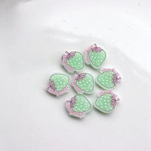Detailed view of light green resin strawberry charms for DIY crafts and hair accessories