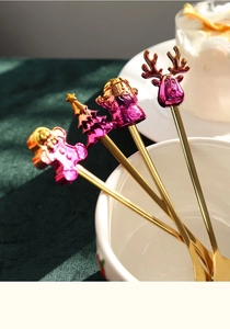 Detail of four golden stainless steel Christmas spoons with colorful festive charms