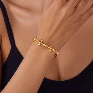 Close-up of a gold-plated stainless steel bracelet featuring delicate cross-shaped links