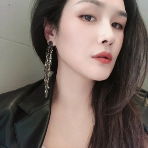 Detailed view of long leaf fringe earrings in dark bronze worn by a fashion model